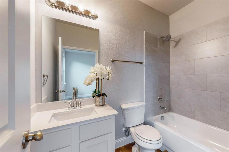 Full bathroom featuring toilet, tiled shower / bath combo, and vanity