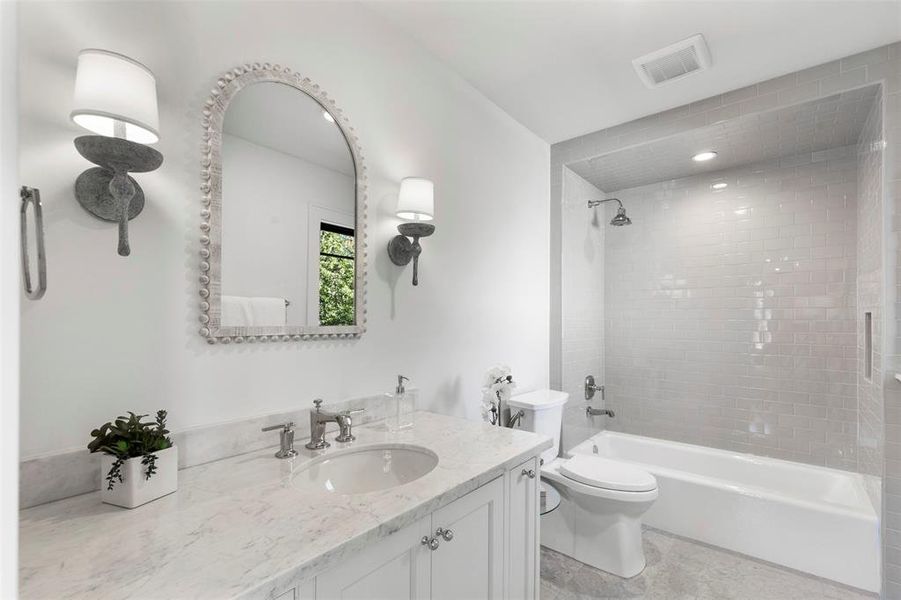 Full bathroom featuring tiled shower / bath, vanity, toilet, and tile floors