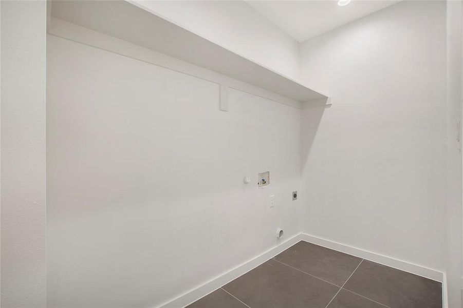 Laundry area with gas dryer hookup, hookup for a washing machine, electric dryer hookup, and dark tile patterned flooring