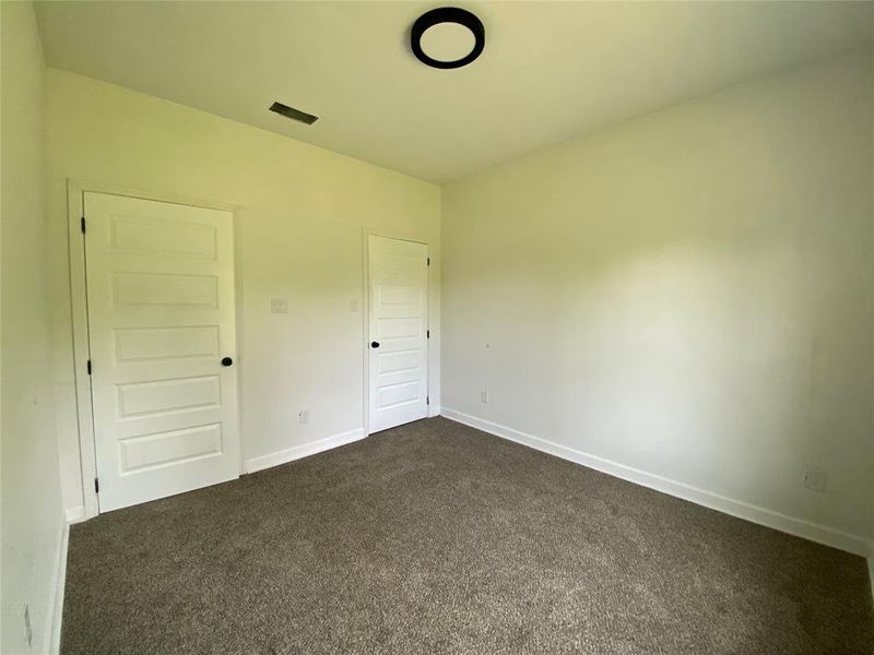 Unfurnished bedroom with dark colored carpet