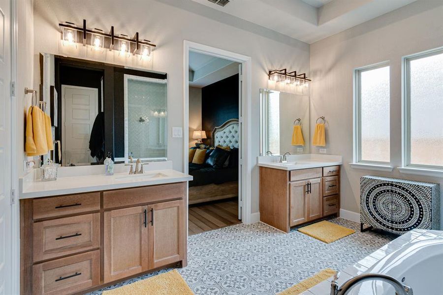 Bathroom featuring a healthy amount of sunlight, vanity with extensive cabinet space, a tub, and tile floors