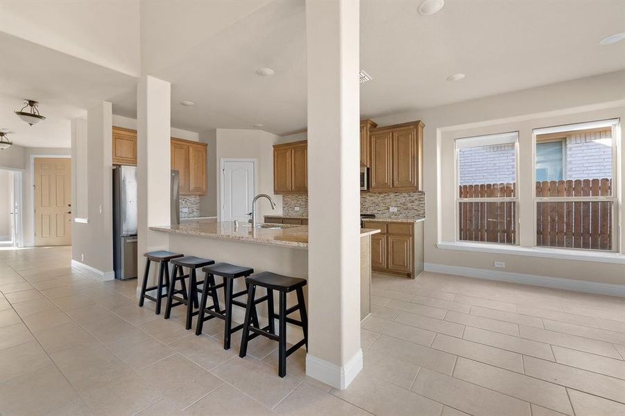 Kitchen with appliances with stainless steel finishes, light stone counters, sink, kitchen peninsula, and a breakfast bar area