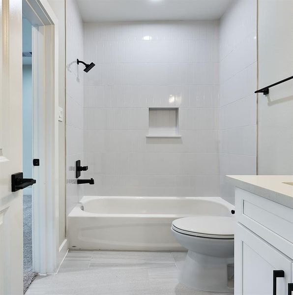 Secondary bathroom with large flooring tile and tile up to the ceiling.