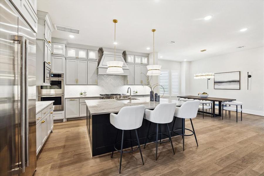 The large center island, adorned with exquisite quartzite countertops serves as the heart of this culinary haven. The kitchen boasts a custom hood vent, top of the line Jenn-Air appliances and upgraded brass hardware and pendant light accents.