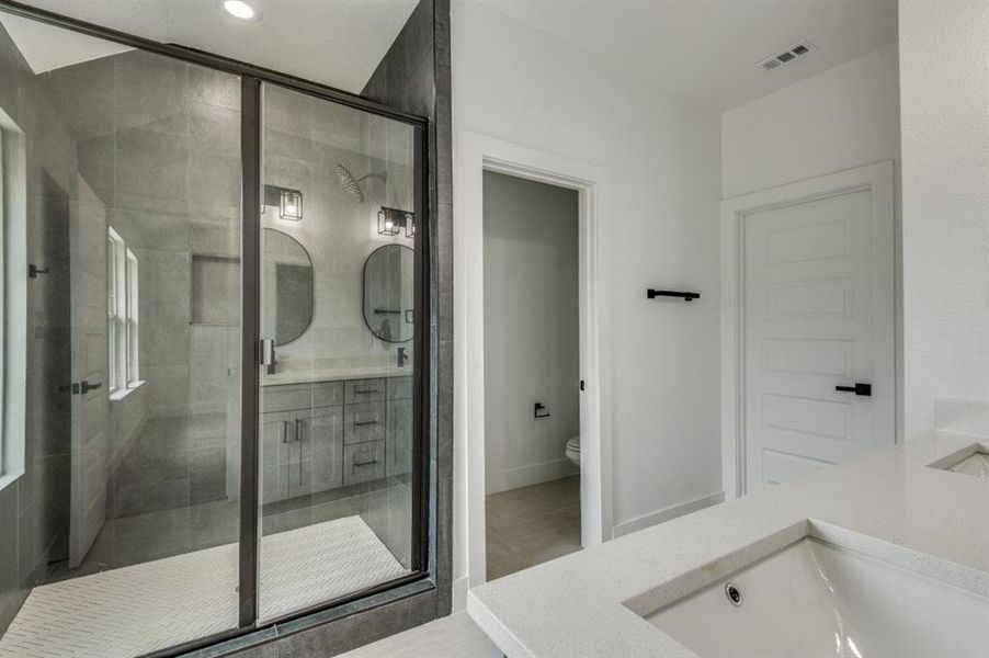 Bathroom featuring walk in shower, vanity, and toilet