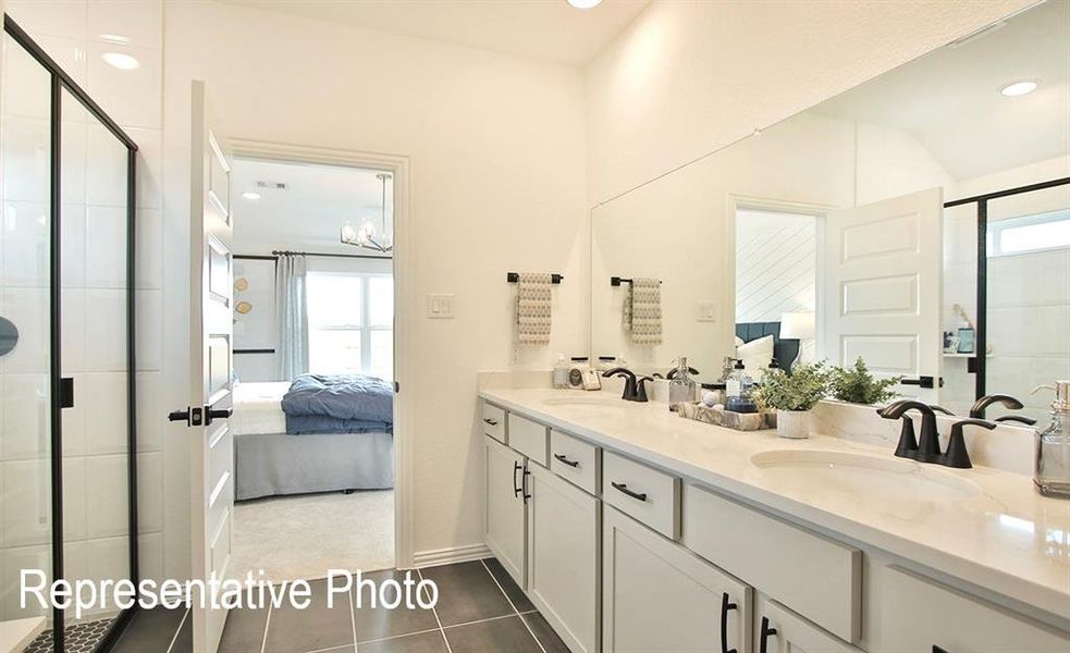 Bathroom featuring a shower with door, a healthy amount of sunlight, vanity, and tile patterned flooring