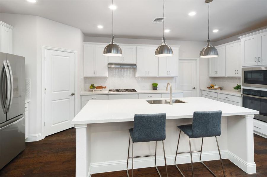 Kitchen with dark wood-type flooring, stainless steel appliances, sink, and white cabinets