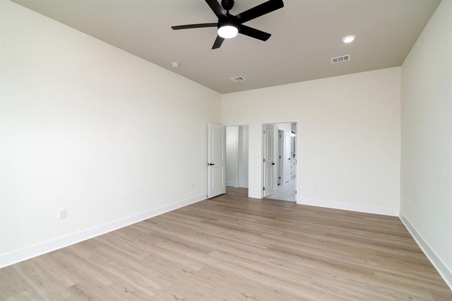 Empty room with ceiling fan and light hardwood / wood-style flooring