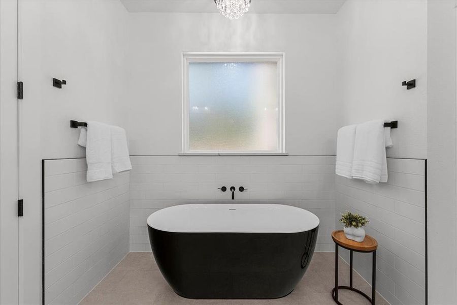 Bathroom with tile walls, a bath, and tile patterned floors