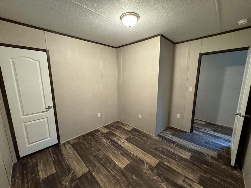 Unfurnished bedroom featuring a textured ceiling and dark hardwood / wood-style flooring