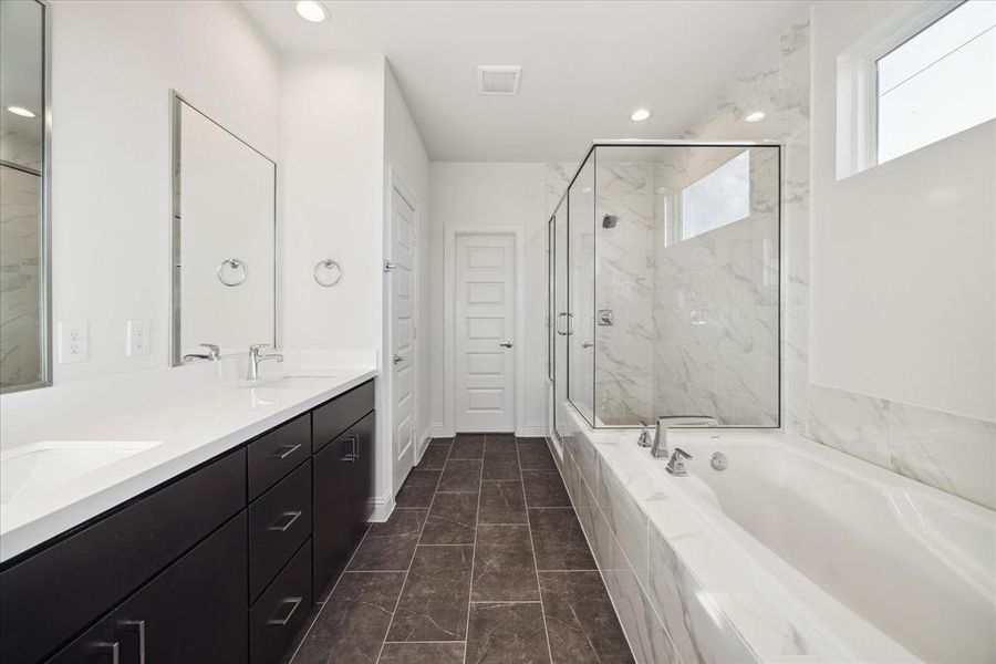 This luxurious primary bathroom features a sleek, modern design. The double vanity offers ample storage and counter space, while the oversized soaking tub invites relaxation.