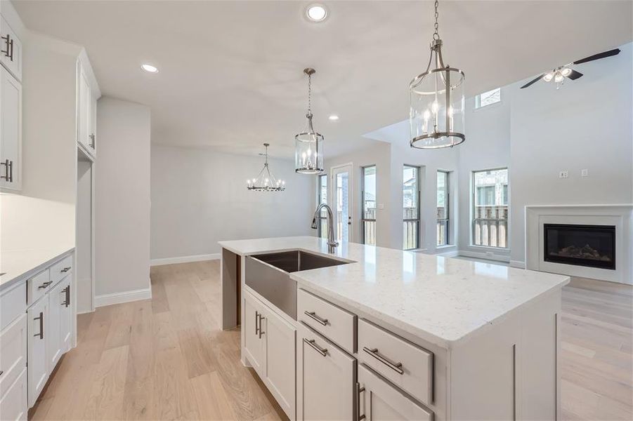 Kitchen with light hardwood / wood-style flooring, hanging light fixtures, and a center island with sink