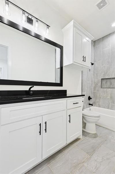 Full bathroom featuring tiled shower / bath, vanity, and toilet