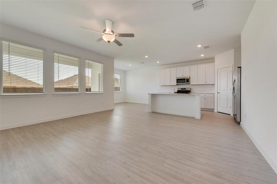 Unfurnished living room with ceiling fan, light hardwood / wood-style flooring, and a healthy amount of sunlight