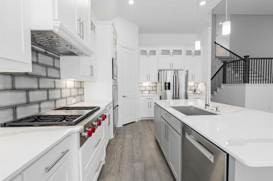 Kitchen featuring stainless steel appliances, hardwood / wood-style flooring, decorative light fixtures, sink, and tasteful backsplash