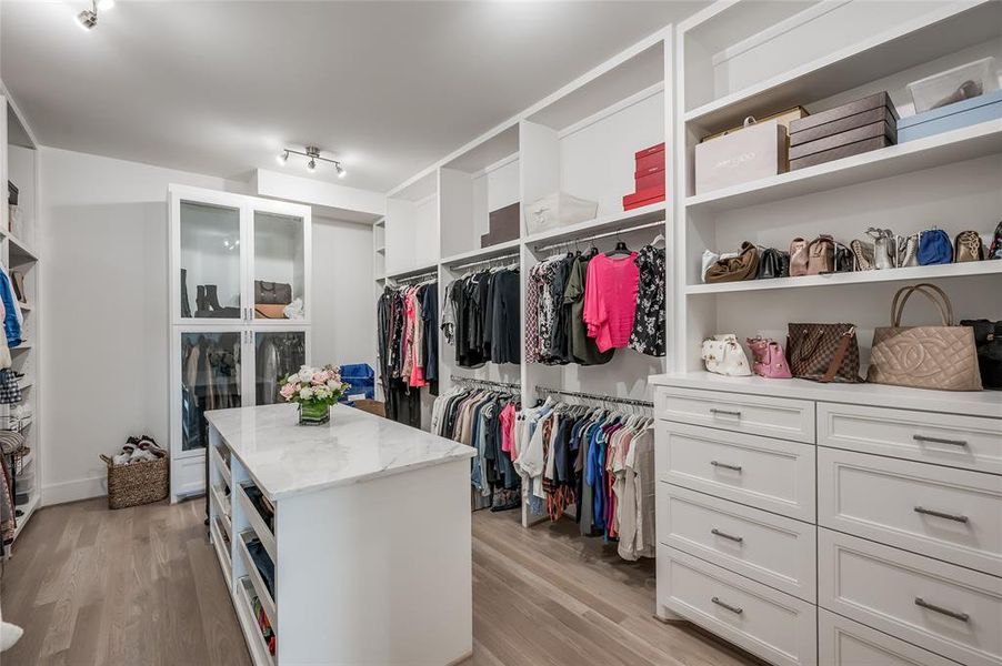 The first of two large primary closets offers abundant hanging space, drawers, shelves, and a packing island.