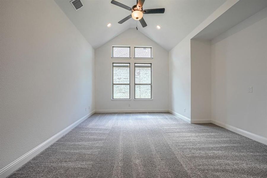 Empty room with vaulted ceiling, carpet, and ceiling fan