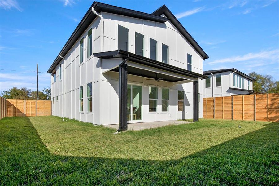 Back of property with ceiling fan and a yard