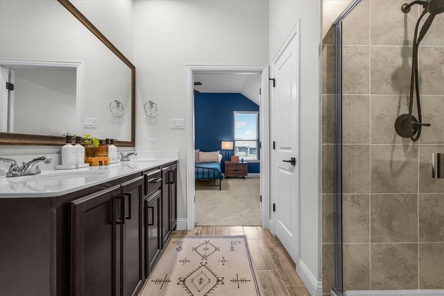 Bathroom with wood-type flooring, vanity, vaulted ceiling, and a shower with shower door