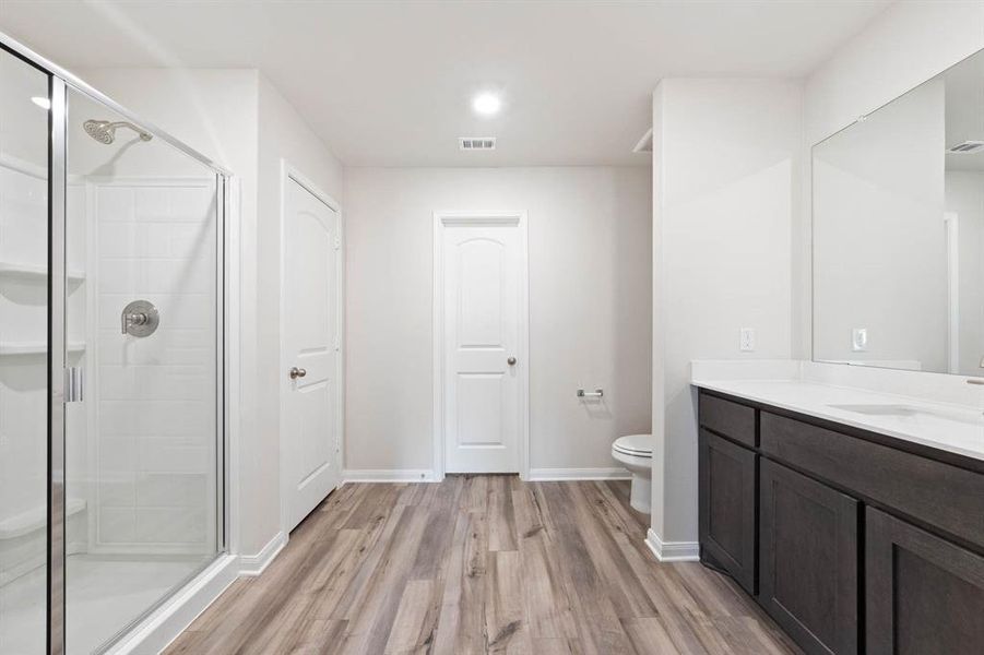 Bathroom with hardwood / wood-style flooring, walk in shower, vanity, and toilet