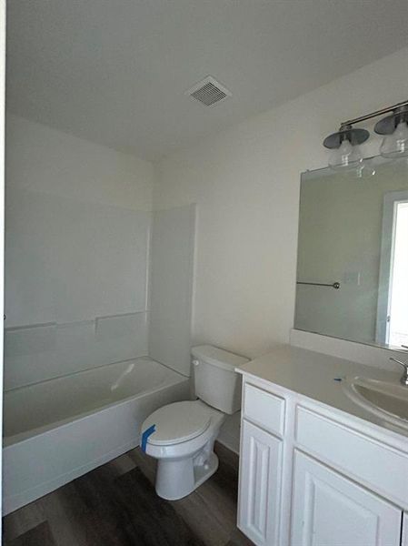 Full bathroom with shower / bathtub combination, wood-type flooring, vanity, and toilet