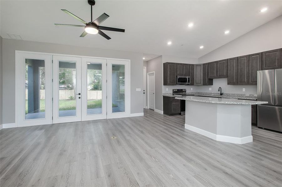 Family room to kitchen area. The custom 8ft glass French Doors open to your private Lanai. The door near the kitchen is to your Laundry room.