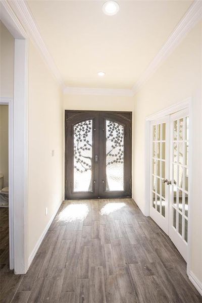 Foyer entrance with ornamental molding, french doors, a wealth of natural light, and dark hardwood / wood-style flooring