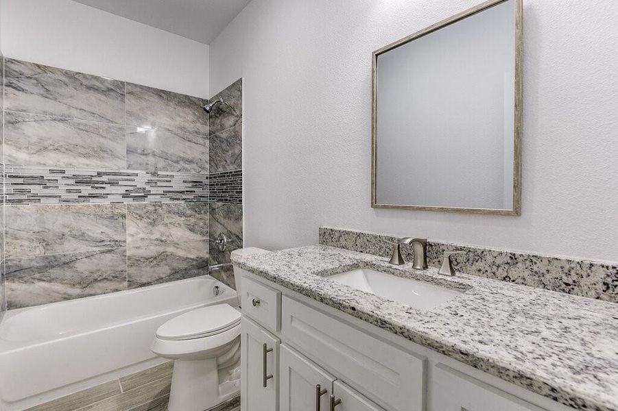 Full bathroom featuring vanity, tiled shower / bath combo, wood-type flooring, and toilet