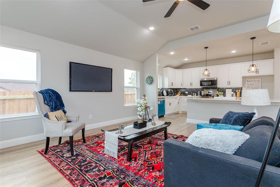 Living room featuring light hardwood / wood-style floors, lofted ceiling, and ceiling fan