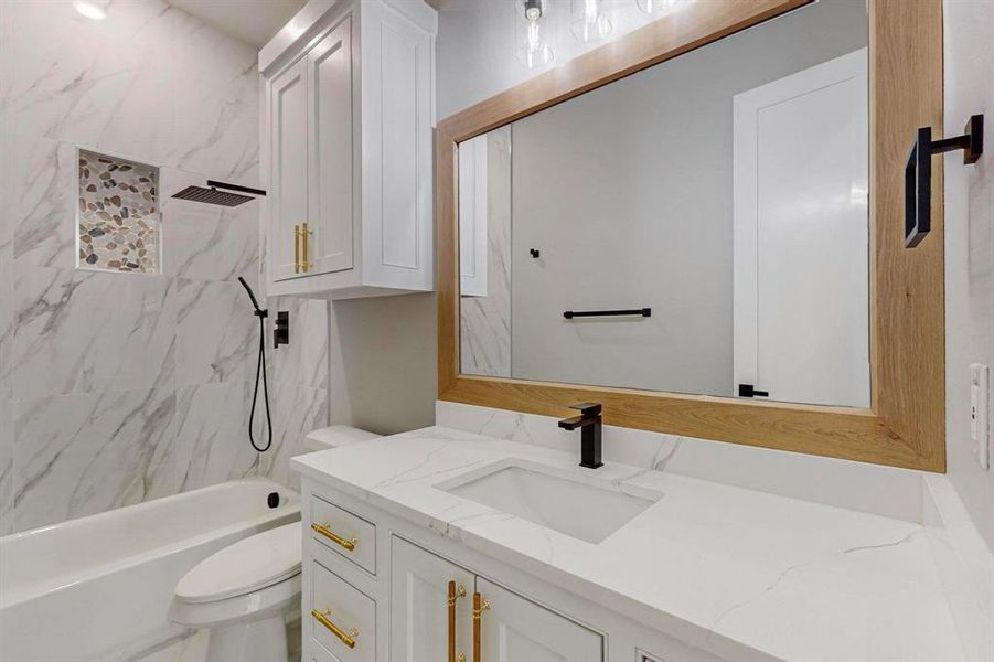 Full bathroom with vanity, tiled shower / bath combo, and toilet