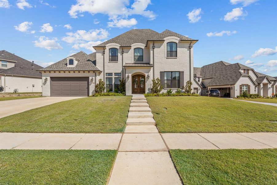 French provincial home with a front lawn and a garage