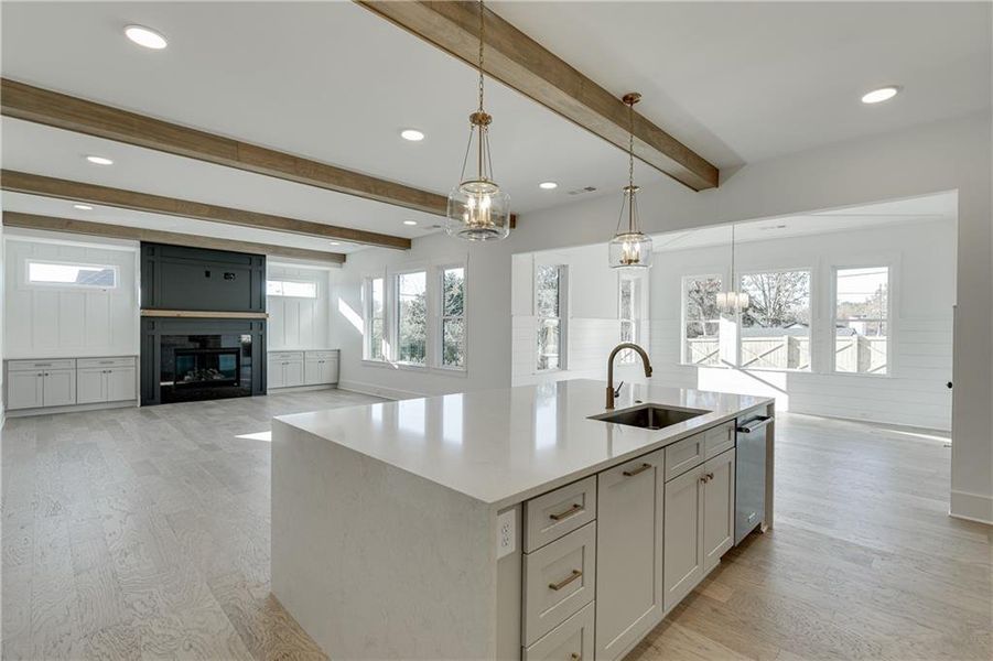 Kitchen with hanging light fixtures, a center island with sink, sink, and light hardwood / wood-style floors