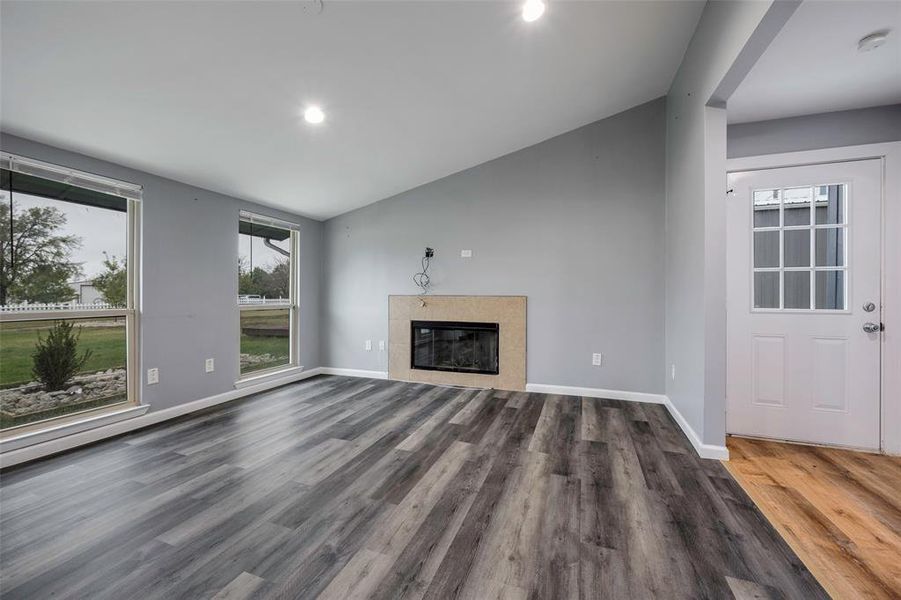 Unfurnished living room featuring dark wood-type flooring and lofted ceiling