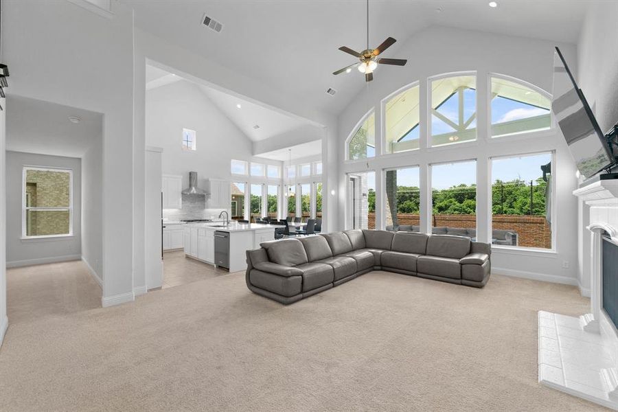 Living room featuring light carpet, high vaulted ceiling, and a healthy amount of sunlight