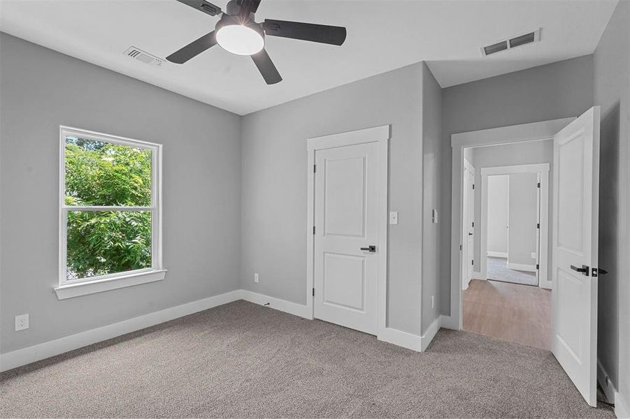 Unfurnished bedroom with light colored carpet and ceiling fan