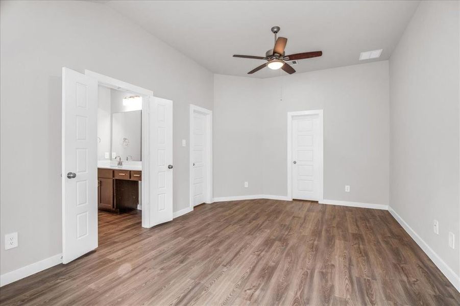 Two separate walk-in closets.  High ceiling and LV wood look flooring highlight primary bedroom.