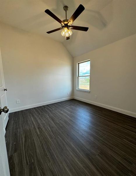 Unfurnished room with ceiling fan, lofted ceiling, and dark wood-type flooring