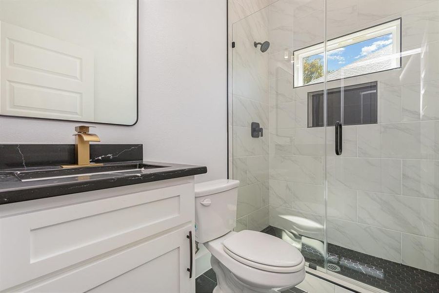 Bathroom with vanity, a shower with shower door, and toilet