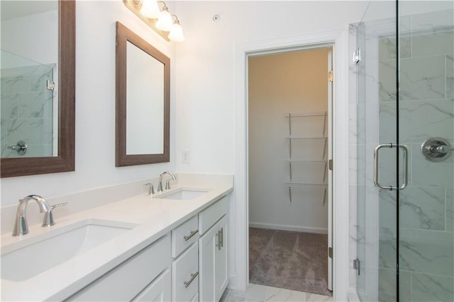 Master Bathroom featuring a walking  shower with door, double vanity, and tile patterned floors not the actual unit