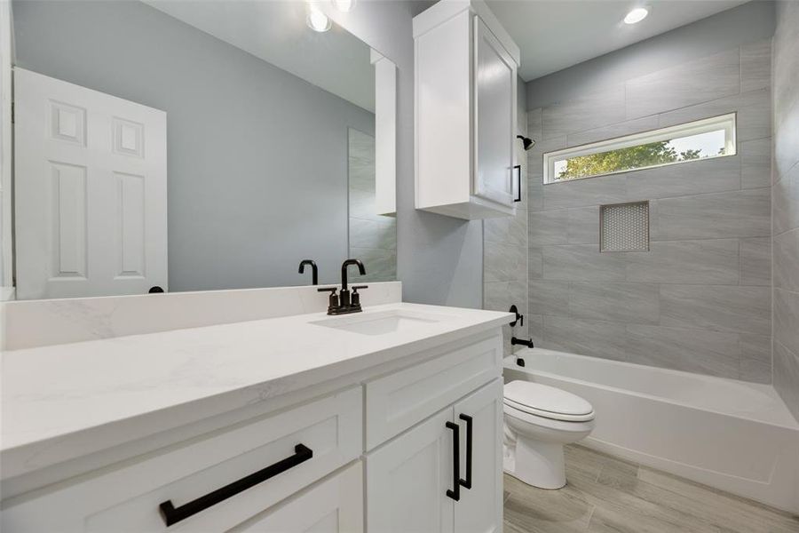 Full bathroom featuring vanity, wood-type flooring, tiled shower / bath, and toilet