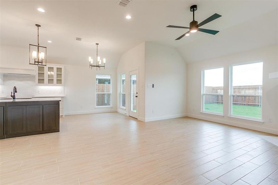 Unfurnished living room featuring lofted ceiling, light hardwood / wood-style floors, sink, and a wealth of natural light