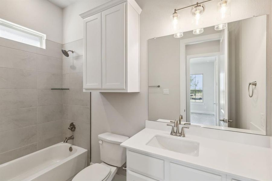 Full bathroom featuring vanity, tiled shower / bath combo, toilet, and plenty of natural light