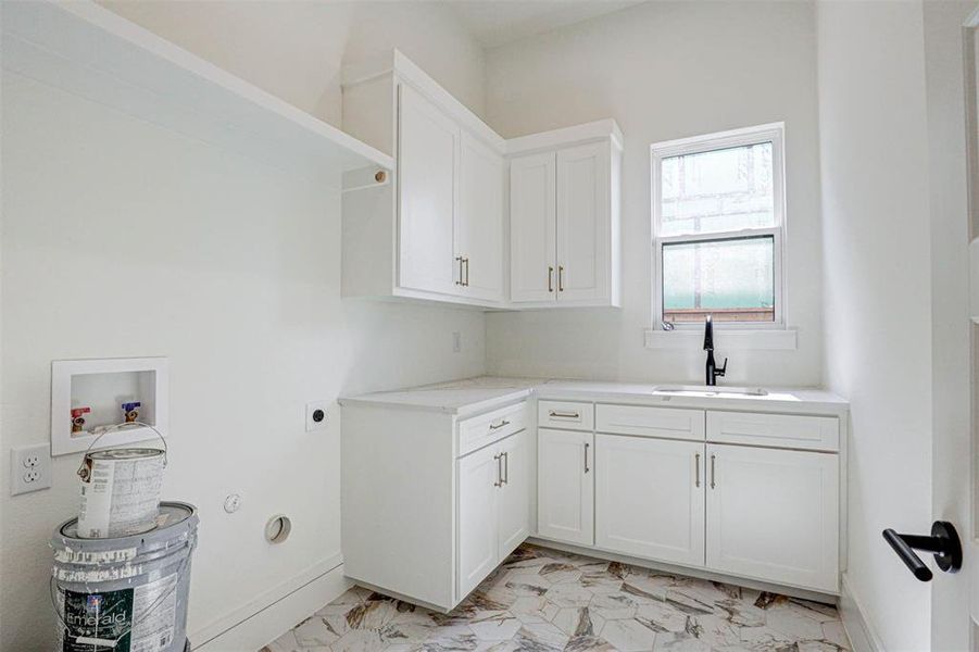 Washroom with hookup for an electric dryer, light tile patterned floors, hookup for a washing machine, cabinets, and sink