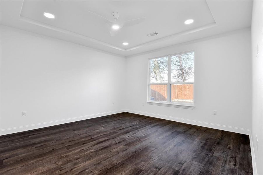 Spare room with dark wood-type flooring, ceiling fan, and a raised ceiling