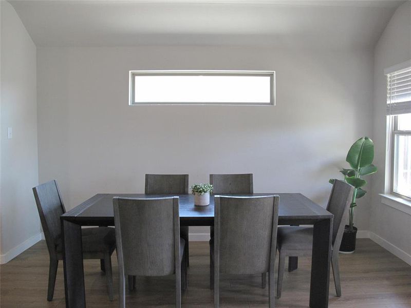 Dining area featuring dark wood-type flooring, lofted ceiling, and a healthy amount of sunlight