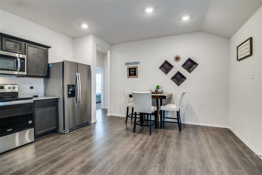 Kitchen featuring lofted ceiling, appliances with stainless steel finishes, and dark hardwood / wood-style flooring