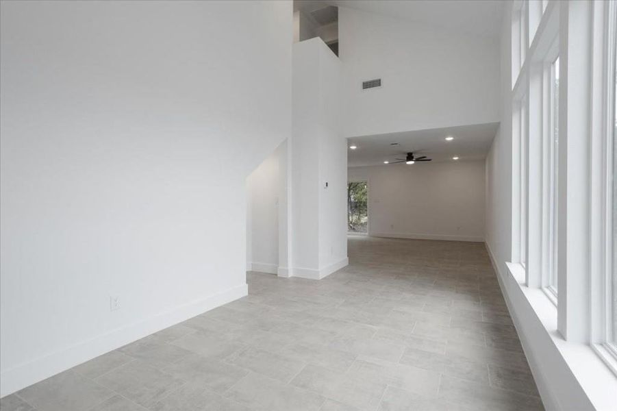 Tiled spare room featuring a high ceiling and ceiling fan