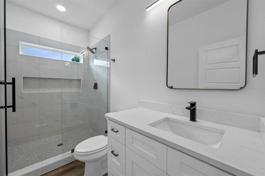 Bathroom with a shower with door, vanity, hardwood / wood-style flooring, and toilet