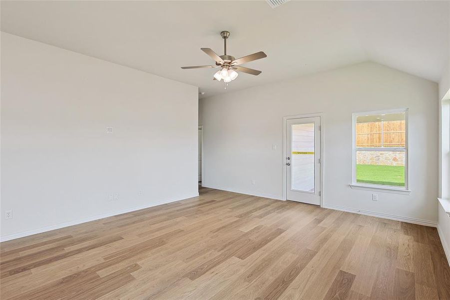 Empty room with lofted ceiling, ceiling fan, and light hardwood / wood-style floors