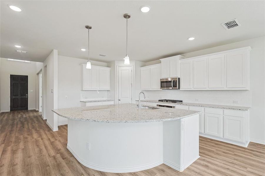 Kitchen with appliances with stainless steel finishes, white cabinets, and light hardwood / wood-style floors